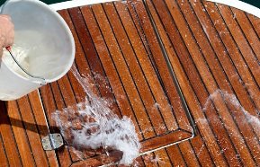 Un cubo de agua vertido en la cubierta de teca de un barco